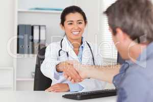 Pretty female doctor shaking a patient's hands