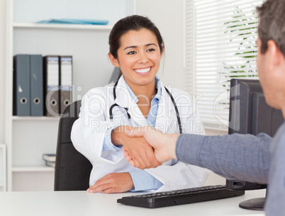 Beautiful female doctor shaking a patient's hands