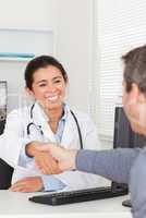 Attractive female doctor shaking a patient's hands