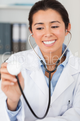 Pretty female doctor using a stethoscope while looking at the ca