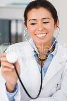 Pretty female doctor using a stethoscope while looking at the ca