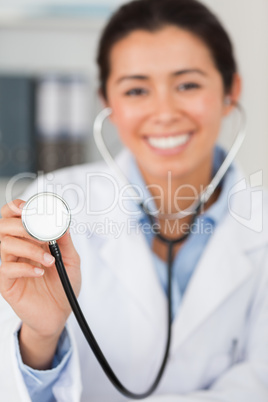 Lovely female doctor using a stethoscope while looking at the ca