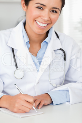 Good looking female doctor writing on a scratchpad