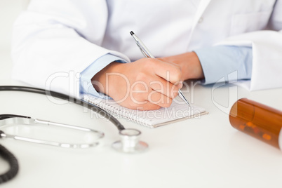 Young female doctor writing on a scratchpad