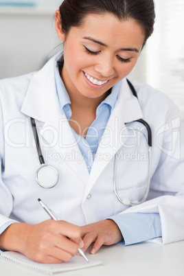 Charming female doctor writing on a scratchpad