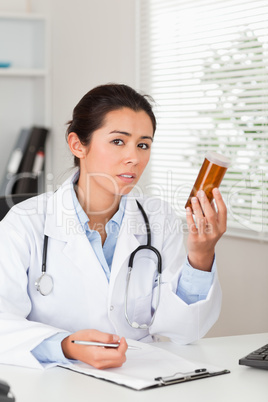 Pretty worried doctor holding a box of pills