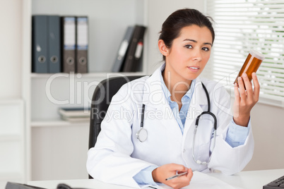 Beautiful pensive doctor holding a box of pills