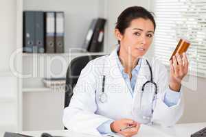 Beautiful pensive doctor holding a box of pills