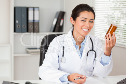 Attractive smiling doctor holding a box of pills