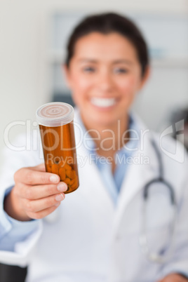 Portrait of an attractive smiling doctor holding a box of pill