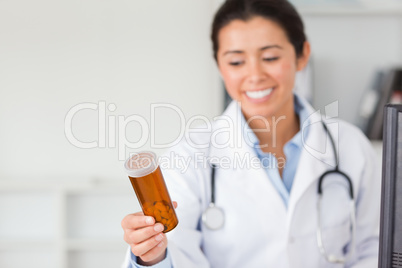 Attractive smiling doctor holding and looking at a box of pills