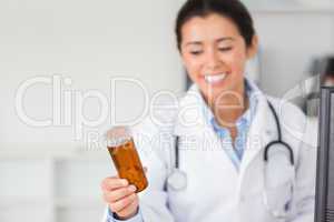 Attractive smiling doctor holding and looking at a box of pills