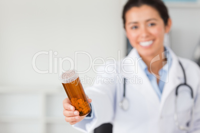 Gorgeous smiling doctor holding a box of pills