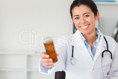 Pretty smiling doctor holding a box of pills