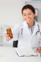 Gorgeous smiling doctor holding a box of pills while sitting