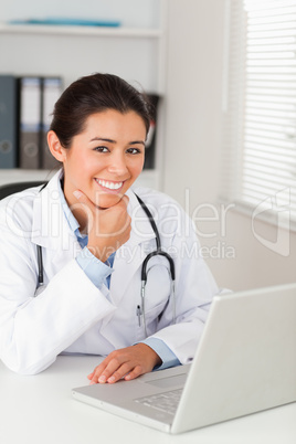 Beautiful female doctor working with her laptop while posing Beautiful female doctor working with her laptop while posing