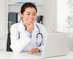 Attractive female doctor working with her laptop while sitting