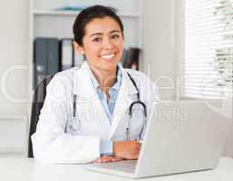 Good looking female doctor working with her laptop while posing