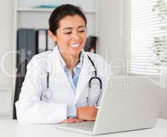 Good looking female doctor working with her laptop while sitting