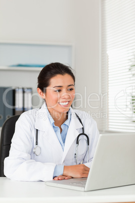 Lovely female doctor working with her laptop while sitting