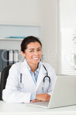 Lovely female doctor working with her laptop while posing