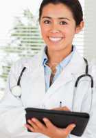 Good looking female doctor with a stethoscope writing on a noteb