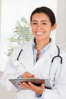 Attractive female doctor with a stethoscope writing on a noteboo