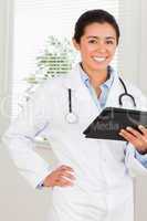 Good looking female doctor with a stethoscope holding a notebook