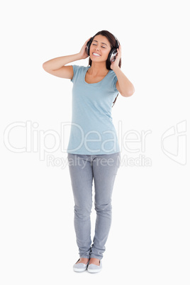 Gorgeous woman using her headphones while standing