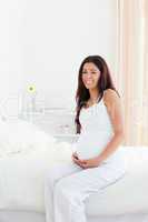 Attractive pregnant woman touching her belly while sitting on a
