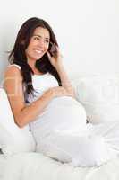 Good looking pregnant woman on the phone while lying on a bed