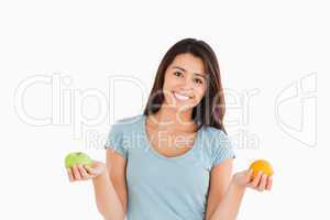 Good looking woman holding an apple and an orange