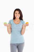 Attractive woman holding an apple and an orange