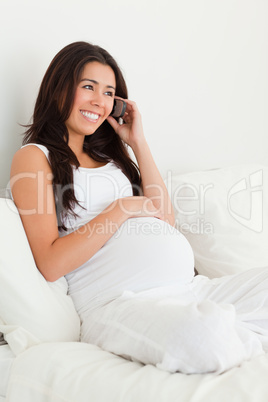 Attractive pregnant woman on the phone while lying on a bed