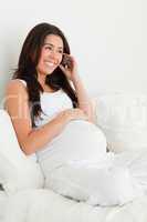 Attractive pregnant woman on the phone while lying on a bed