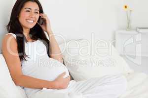 Gorgeous pregnant woman on the phone while lying on a bed