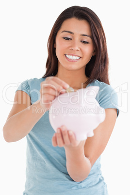 Beautiful woman inserting a coin in a piggy bank