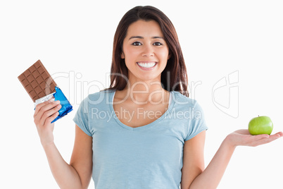 Lovely female holding a chocolate bar and an apple