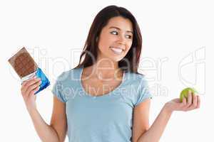 Attractive female holding a chocolate bar and an apple