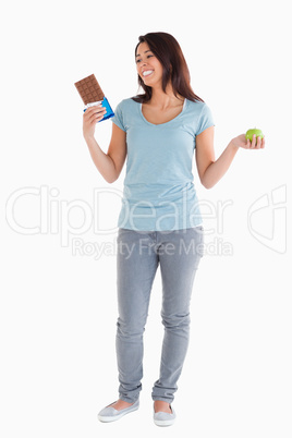Gorgeous female holding a chocolate bar and an apple