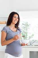 Beautiful pregnant woman enjoying a bowl of cereals while standi