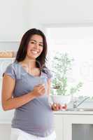 Good looking pregnant woman enjoying a bowl of cereals while sta