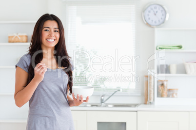 Charming woman enjoying a bowl of cereals while standing