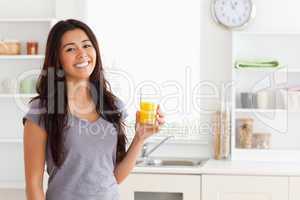 Attractive woman holding a glass of orange juice while standing