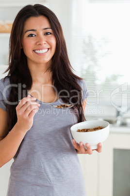 Attractive female enjoying a bowl of cereals while standing