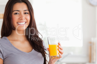 Good looking woman holding a glass of orange juice while standin
