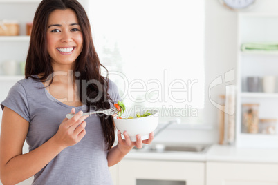 Beautiful woman enjoying a bowl of salad while standing