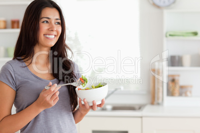 Attractive woman enjoying a bowl of salad while standing