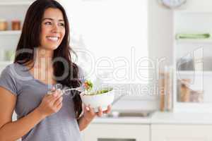 Attractive woman enjoying a bowl of salad while standing