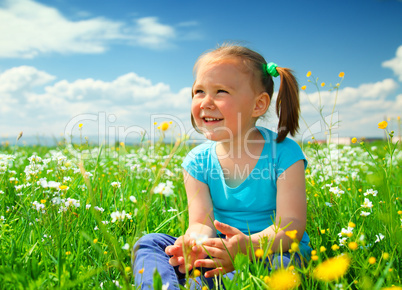 Little girl is playing on green meadow
